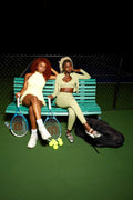 S.I.A.F HAUS models on a tennis court bench representing the Hausmate Pass membership.
